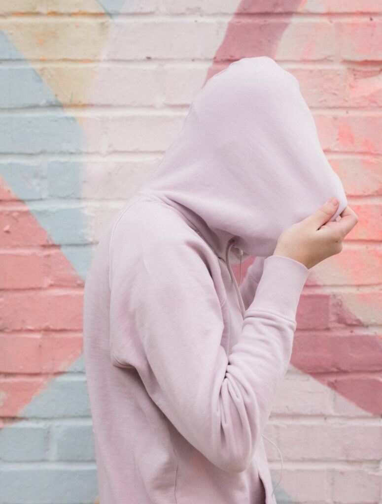 Shy Introverted Teen Pulling Hoodie Fully Over Her Head and pastel colors only